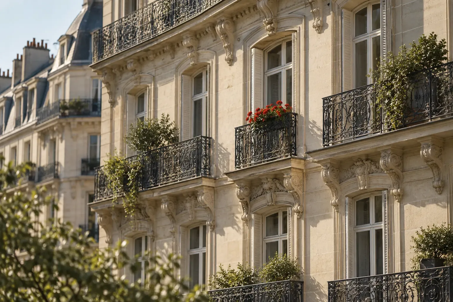 Façade d’immeuble haussmannien à balcons, géraniums rouges à une fenêtre